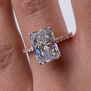 Radiant cut diamond ring with pavé band and four-prong setting